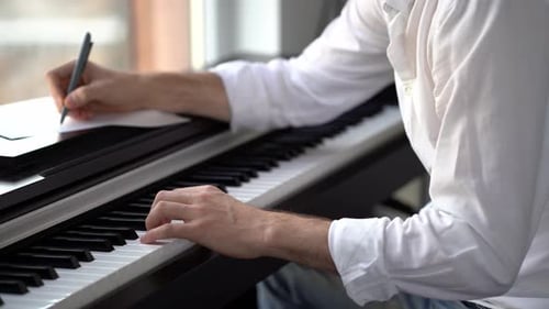 Man Playing Piano and Writing Song