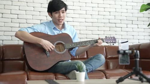 Young Adult Plays Guitar for Smartphone Video