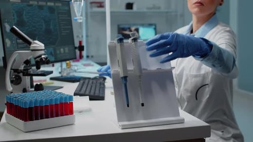 Close Up of Scientist Using Micropipette at Laboratory Desk