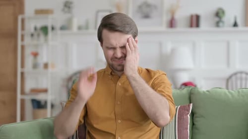 Man Experiencing Headache while Sitting on a Couch
