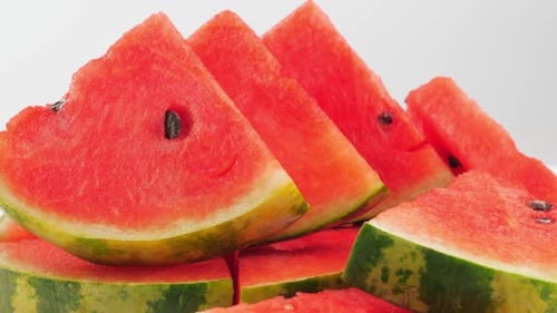 Haufen frisch geschnittener Wassermelonen auf weißem Hintergrund.