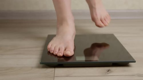 Feet of a woman standing on the scales for weighing.