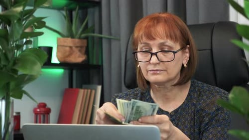 Woman Counting Dollars in Front of Laptop