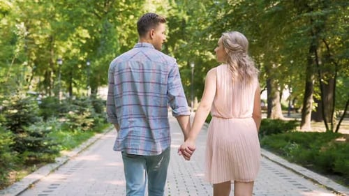 Couple in Love Strolling Through Beautiful Summer Park, Gently Holding Hands