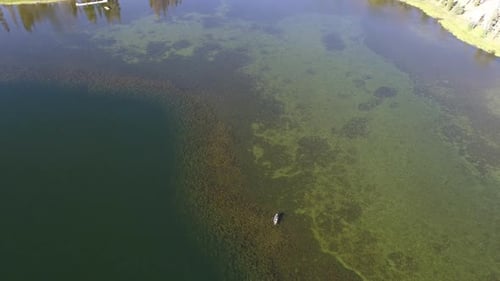 Fly away over lake with boat expanding the view