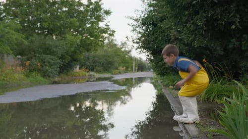 Summer Holiday, Cheerful Barefoot Boy Enjoying Games in Puddle Jumping and Laughing By Road o