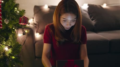 Woman Opens a Christmas Gift with a Smile
