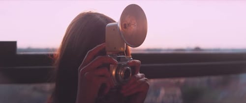 Woman Taking Photo with Vintage Camera at Sunset