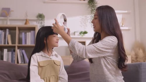 Woman Helps Girl With Headphones in Living Room
