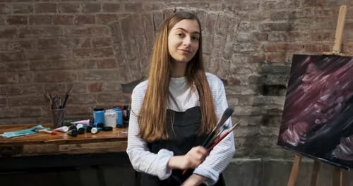 Portrait of Talented Innovative Pretty Female Artist with Brush and Her Canvas on Background