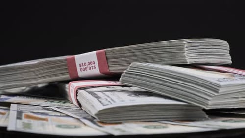 Bundles of Dollars Lying on a Pile of Money and Rotate on Black Background