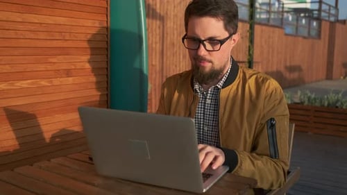 Young Adult Working on Laptop Outdoors in Daytime