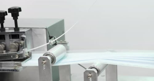 Machine With Steel Roller Pressing Pleated Face Mask Fabric In A Factory. close up