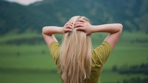 Lady Traveler Adjusts Long Hair Standing at Mountain Valley