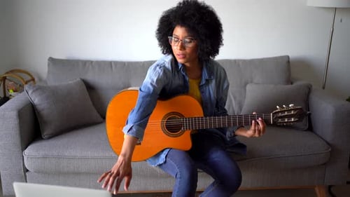 Young Woman Plays Guitar at Home