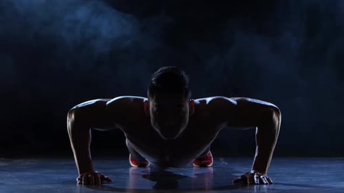 Muscular Man Doing Push-Ups in Smoky Dark Room