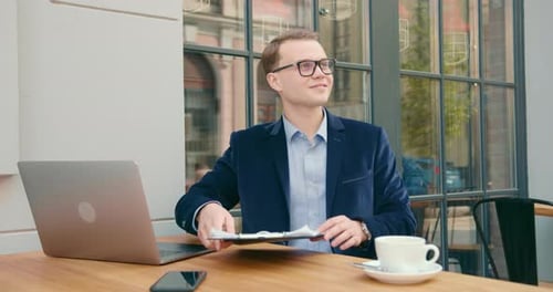 A Businessman Is Sitting in a Cafe and Working