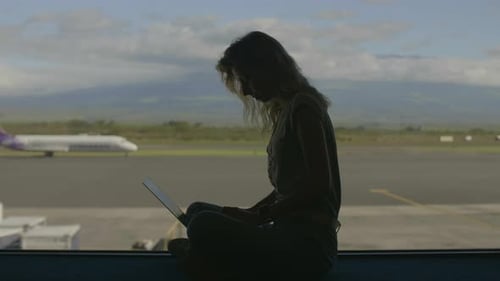 Silhouette of Woman Using Laptop at Airport Window