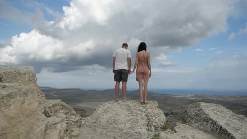 A Couple of Travelers Stand on Top of the Mountain and Holding Hands
