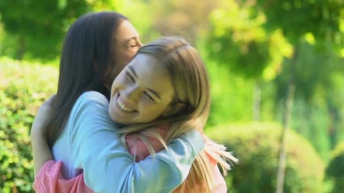 Two Women Friends Embracing in Sunny Park