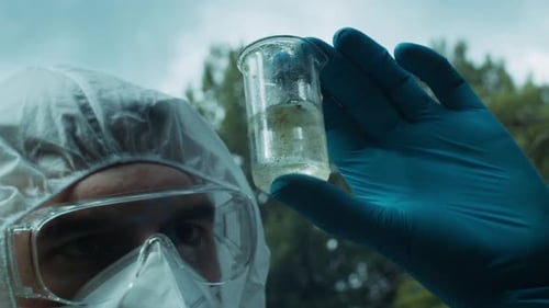 Chemist in Ppe Looking at Flask with Solution Water Analysis From Swamp Wearing Protective Suit and