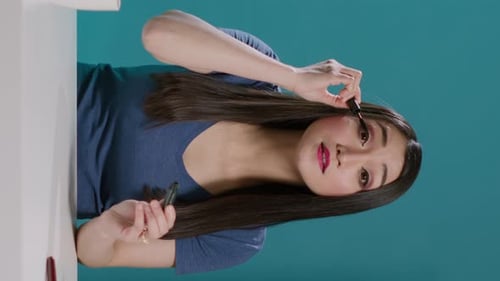 Vertical Video POV of Content Creator Using Mascara for Makeup Tutorial