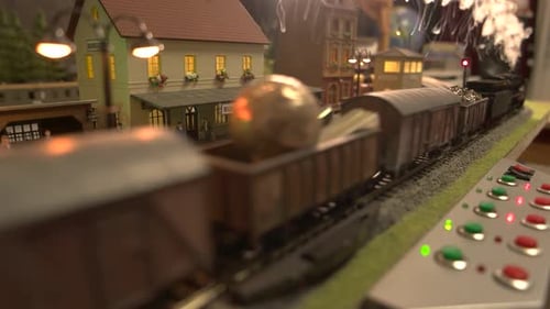 Trem modelo com vapor passando pela estação ferroviária.