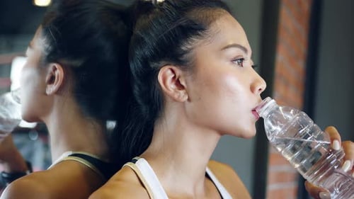 Young Woman Drinks Water in Gym after Workout