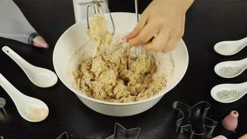 Frauenhände nehmen Teig von Mischerklingen ab