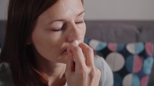 Woman Using Nasal Spray Close Up Indoors