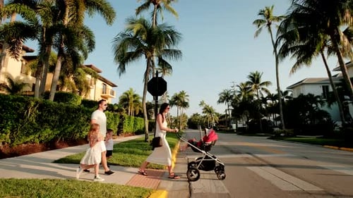 Família jovem com um carrinho de criança cruza a rua