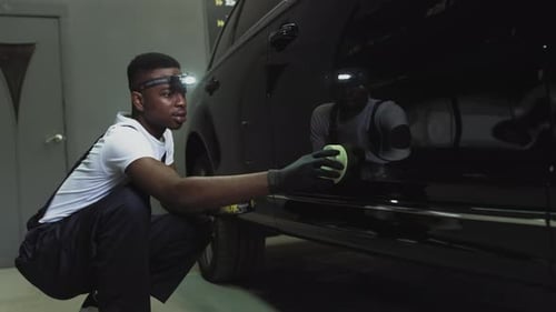 Young Adult Cleaning Black Car in Garage