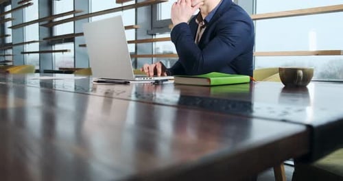 Concerned Man Working on Laptop Computer and Looking Away Thinking Solving Problem at Office