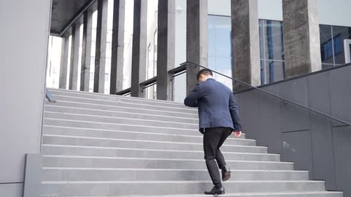 Person in Suit Walking Up Stairs in City