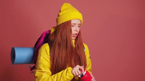 Tired Redhaired Ginger Woman in Pink Studio Background Wearing Yellow Windbreaker Jacket with Hat