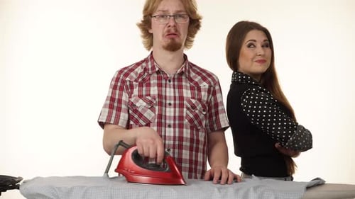 Man Ironing as Woman Smiles