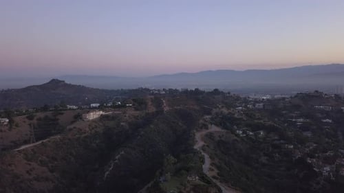 Vista aérea sobre las colinas de Hollywood al amanecer con vistas a las colinas y el valle y líneas eléctricas en Los