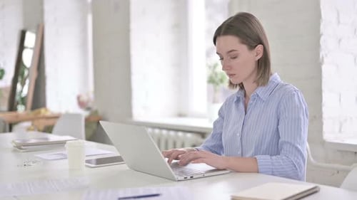 Focused Young Woman Working on Laptop in Modern Office