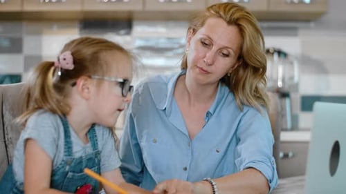 Mother Helping Daughter with Homework in Kitchen