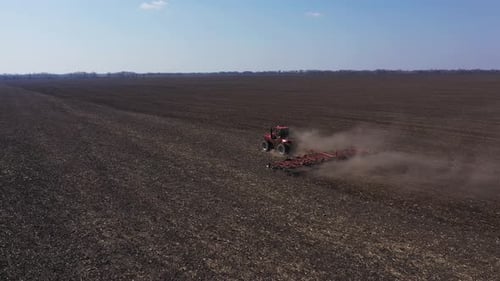 Red Tractor Working in Field at Springtime Aerial View