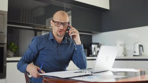 Man Working at Home Using Laptop and Phone