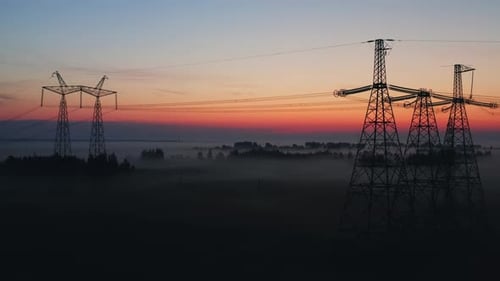Aerial View Silhouettes High Voltage Steel Power Pylons in Field Covered with Fog Countryside