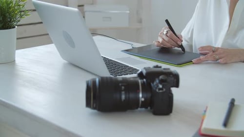 Graphic Designer Works at Desk With Laptop and Tablet