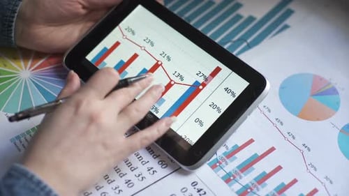 Hand reviews graphs and data on tablet device