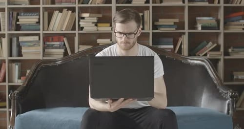Slowmo Portrait of Serious Absorbed Man Using Laptop in Comfortable Library. Front View of