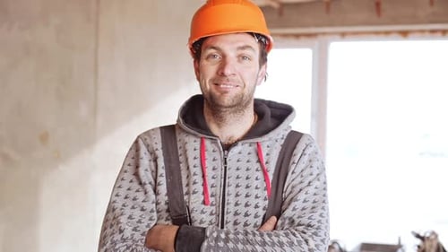 Smiling Construction Worker with Arms Crossed Indoors