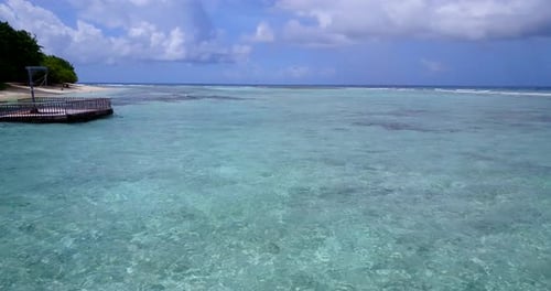 Wide birds eye tourism shot of a white sand paradise beach and aqua turquoise water background in 4K