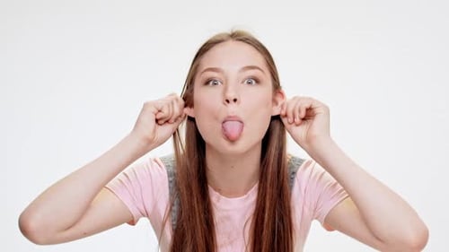 Jeune belle fille montrant la langue en riant sur fond blanc