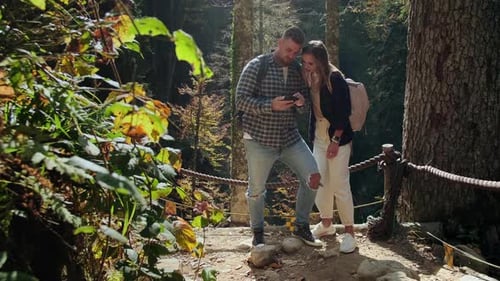 Two Tourists are Visiting Beautiful and Picturesque Natural Park at Autumn Sunny Day