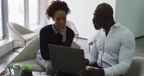 Diverse male and female business colleagues talking, man using laptop in office